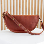 Brown leather handbag on a white surface with a wooden background