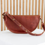 Brown leather handbag on a white surface with a wooden background