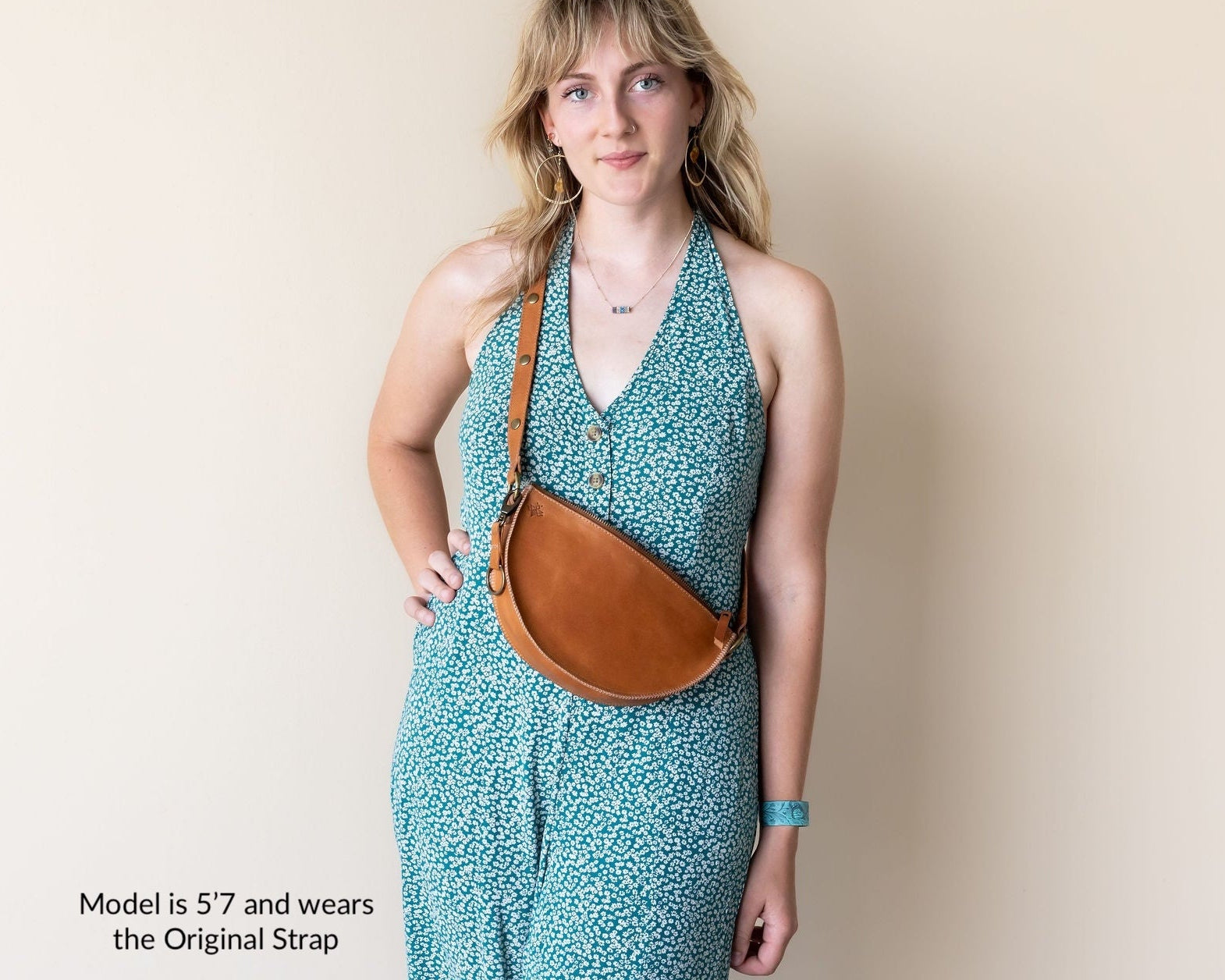 Woman wearing a turquoise dress with a brown leather bag on a beige background