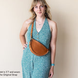 Woman wearing a turquoise dress with a brown leather bag on a beige background
