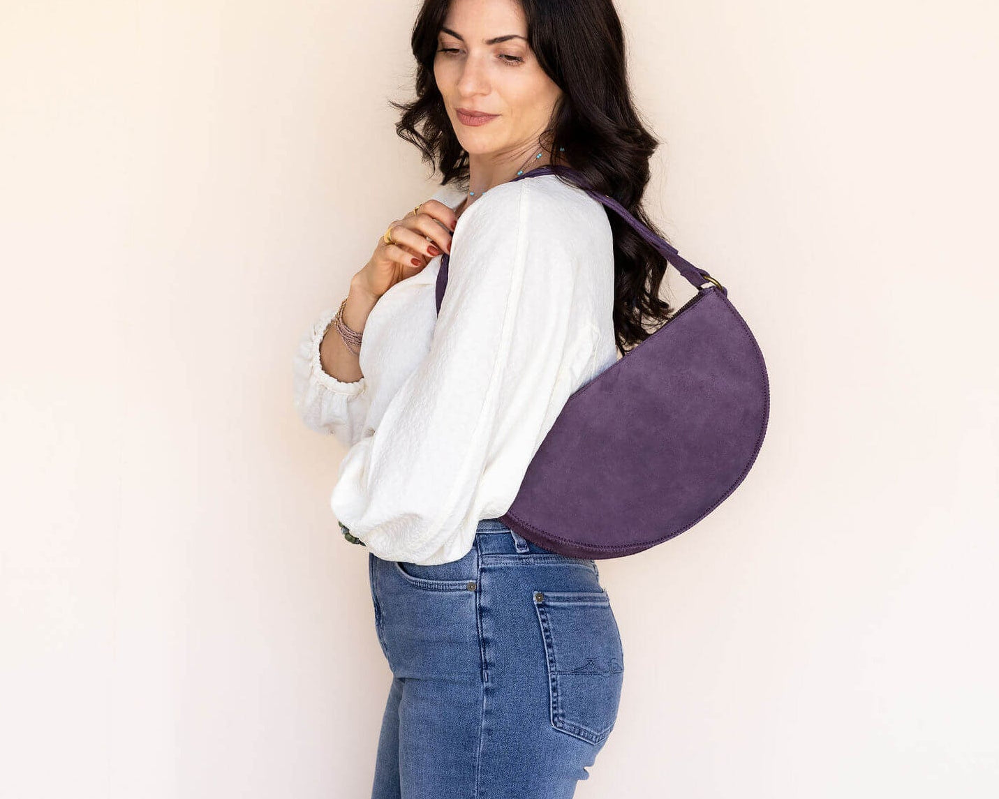 Woman wearing a purple crossbody bag against a plain background