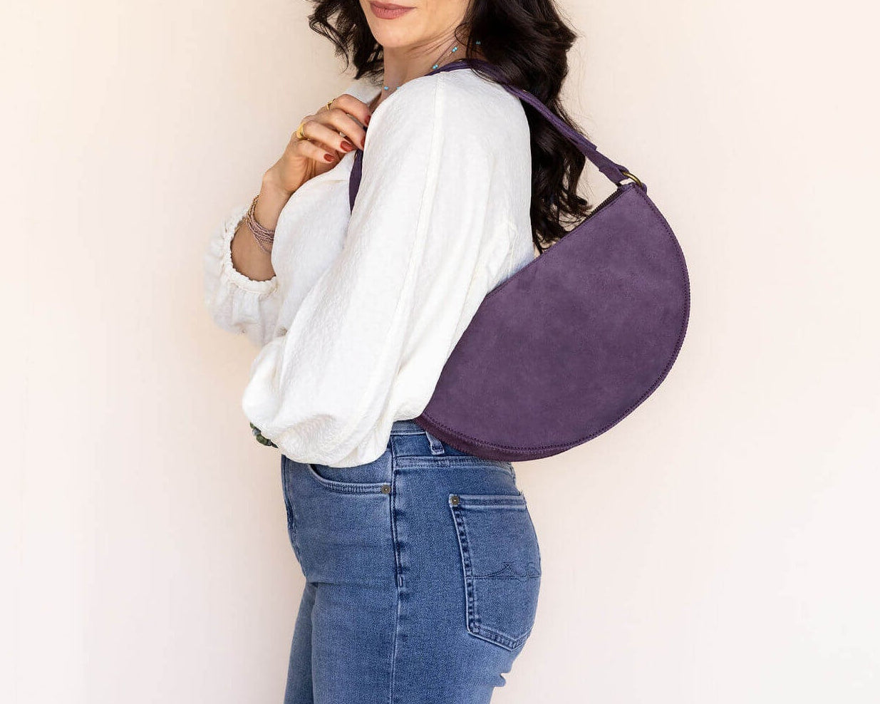 Woman wearing a purple crossbody bag against a plain background