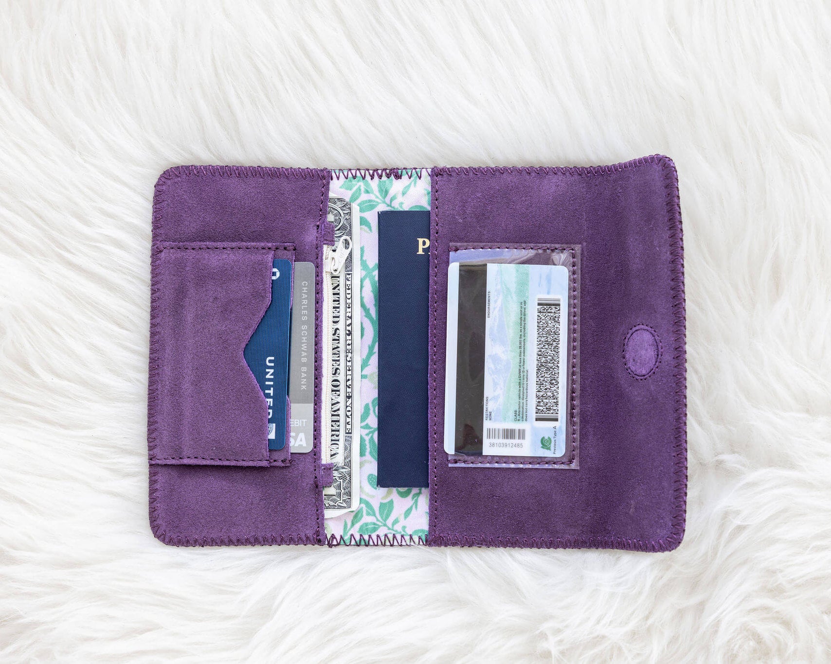 Purple wallet with cards and a passport on a white fur surface