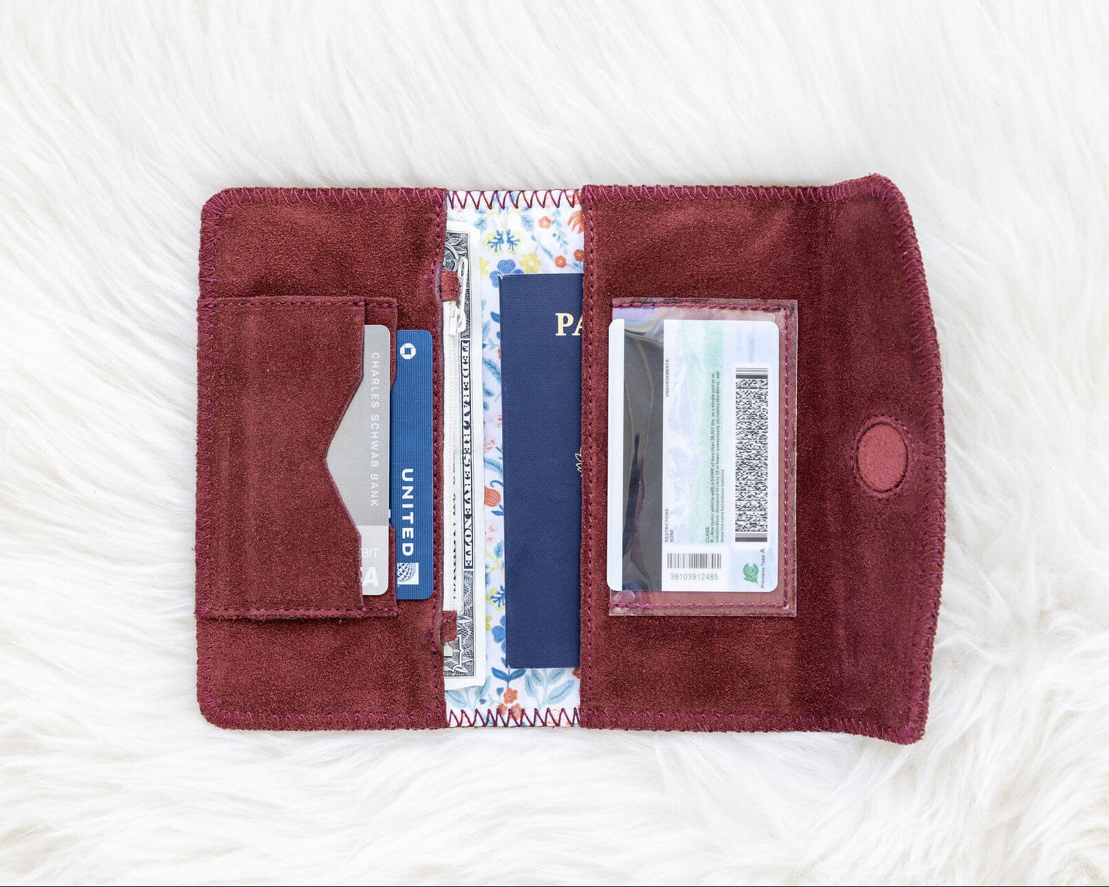 Open red wallet with cards and a passport on a white textured surface