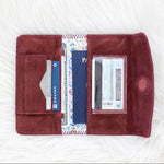 Open red wallet with cards and a passport on a white textured surface