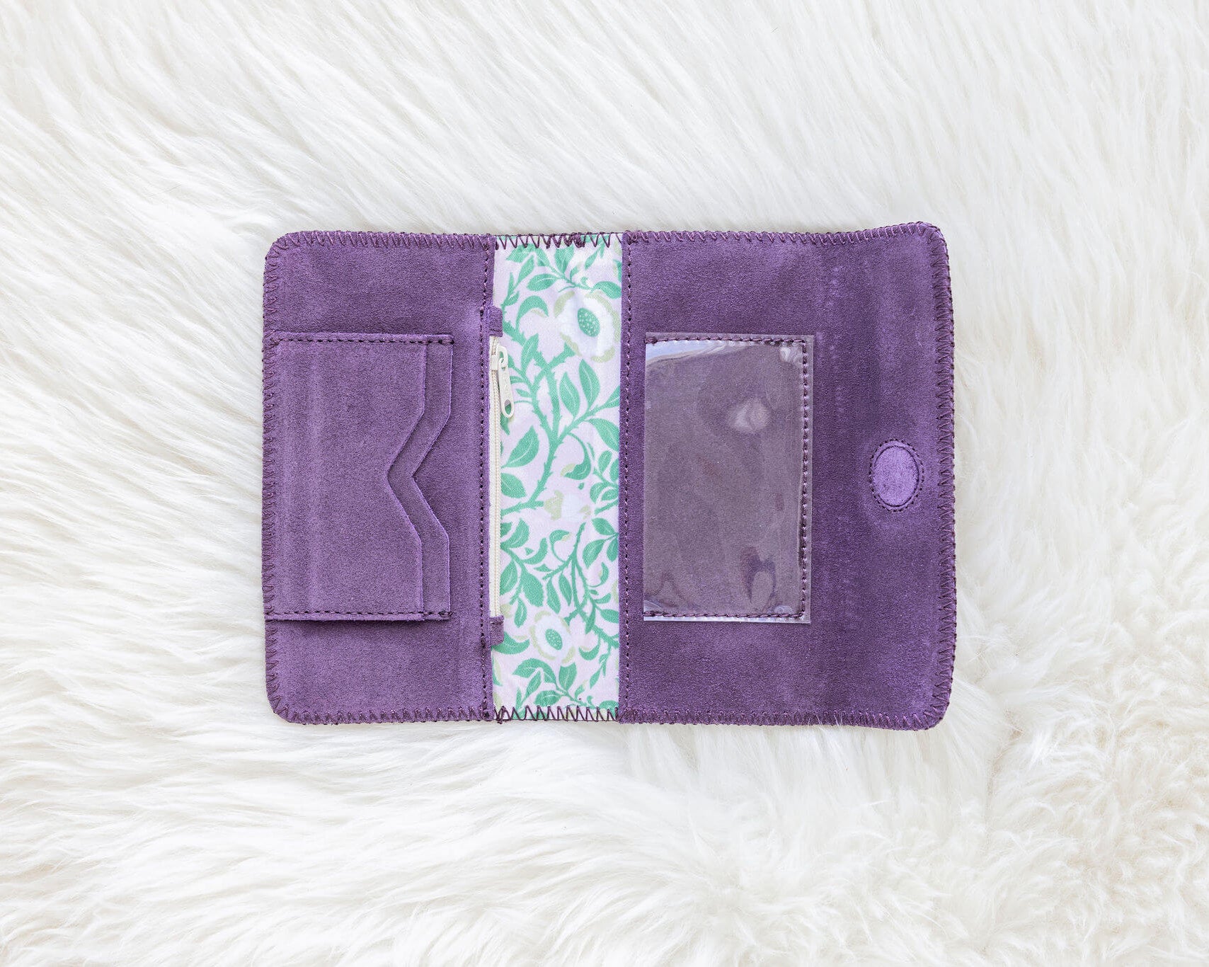 Purple fabric wallet with a floral pattern on a white textured background