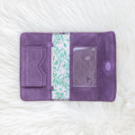 Purple fabric wallet with a floral pattern on a white textured background
