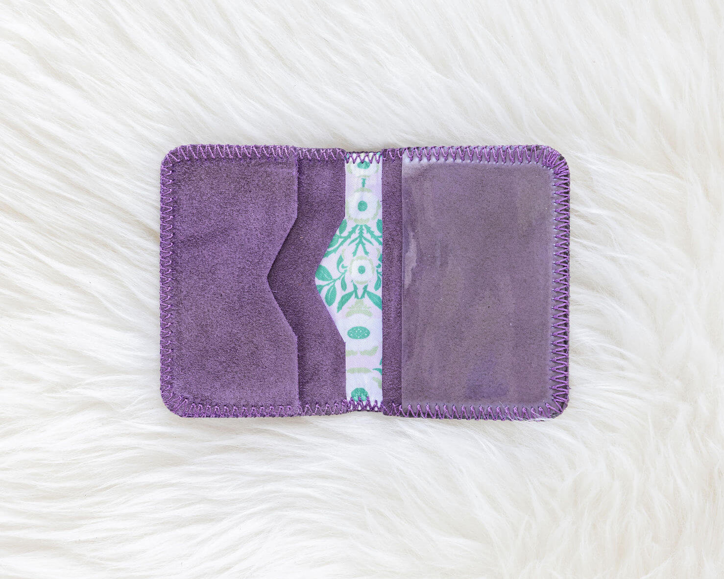 Purple fabric pouch with a patterned interior on a textured white background