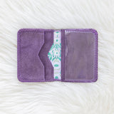 Purple fabric pouch with a patterned interior on a textured white background