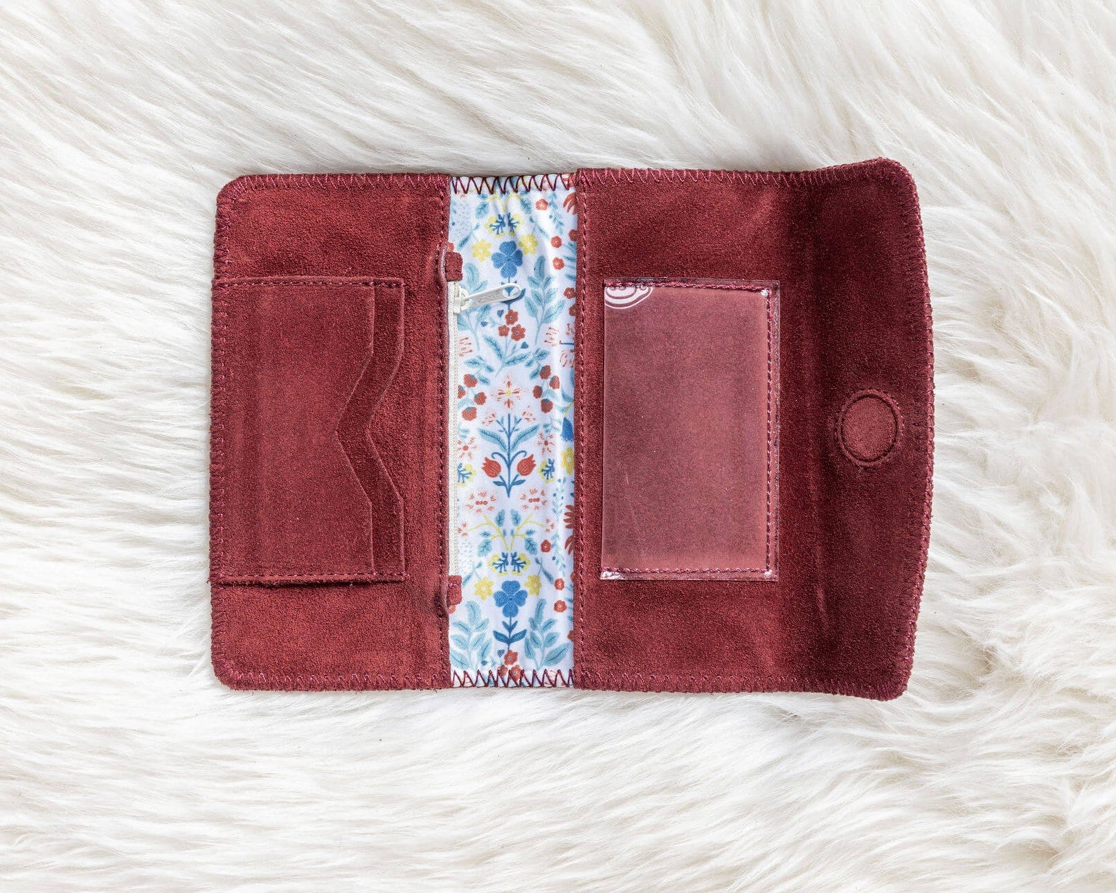 Maroon wallet with floral lining on a white textured surface