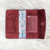Maroon wallet with floral lining on a white textured surface