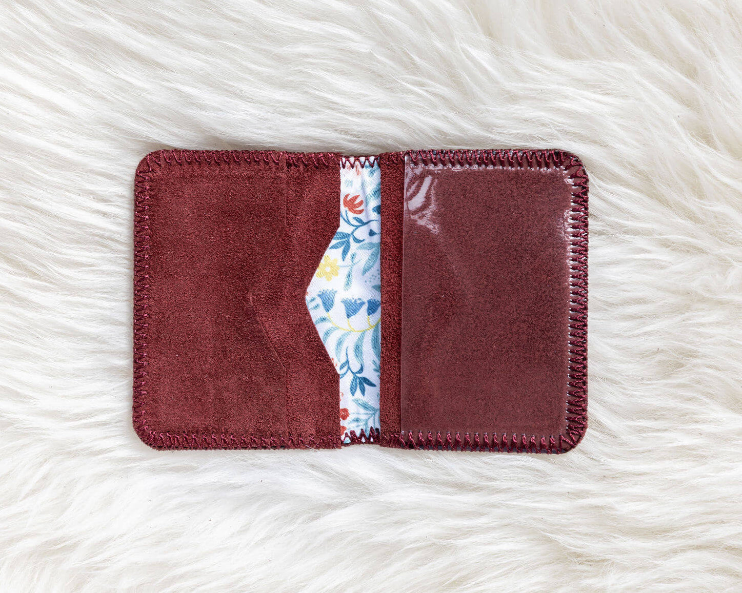 Maroon cardholder with floral interior on a white textured surface