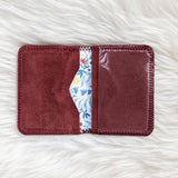 Maroon cardholder with floral interior on a white textured surface