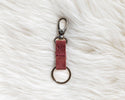 Red leather keychain with metal clasp on a white fur surface