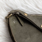 Close-up of a gray leather clutch bag with gold accents on a white fur surface