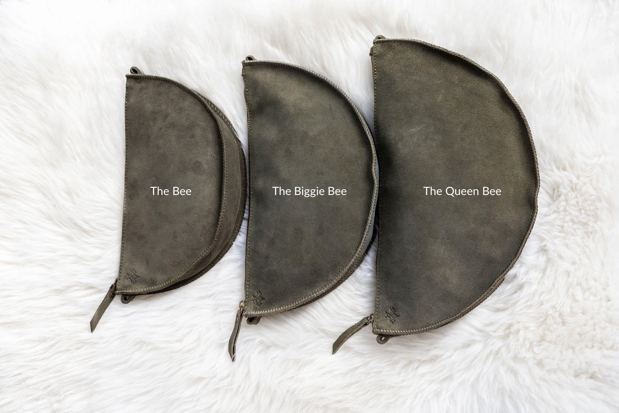 Three dark gray pouches labeled 'The Bee', 'The Biggie Bee', and 'The Queen Bee' on a white textured background.