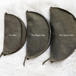 Three dark gray pouches labeled 'The Bee', 'The Biggie Bee', and 'The Queen Bee' on a white textured background.