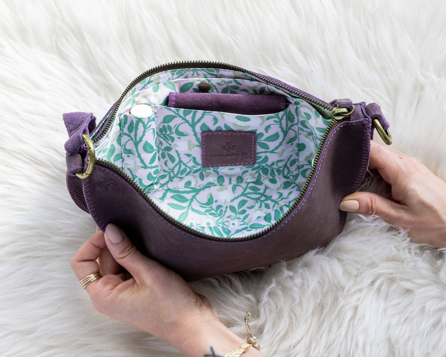 Purple handbag with floral pattern on a white fluffy surface