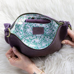 Purple handbag with floral pattern on a white fluffy surface