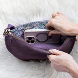 Person placing a phone into a purple pouch on a white fur surface