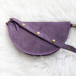 Purple leather bag with gold studs on a white fluffy surface