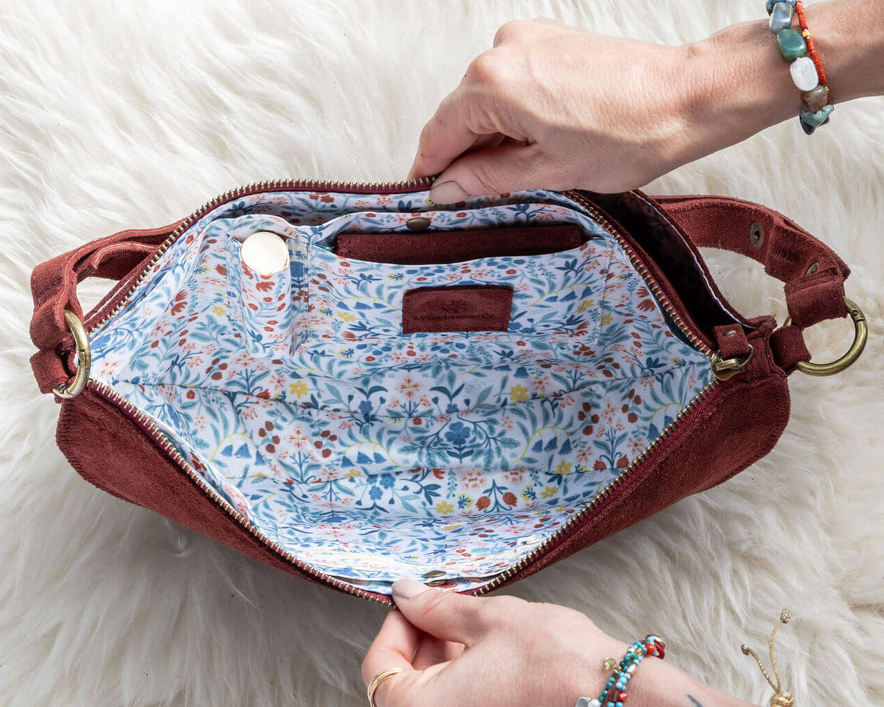 Red handbag with floral interior on a white fluffy surface