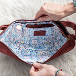 Red handbag with floral interior on a white fluffy surface