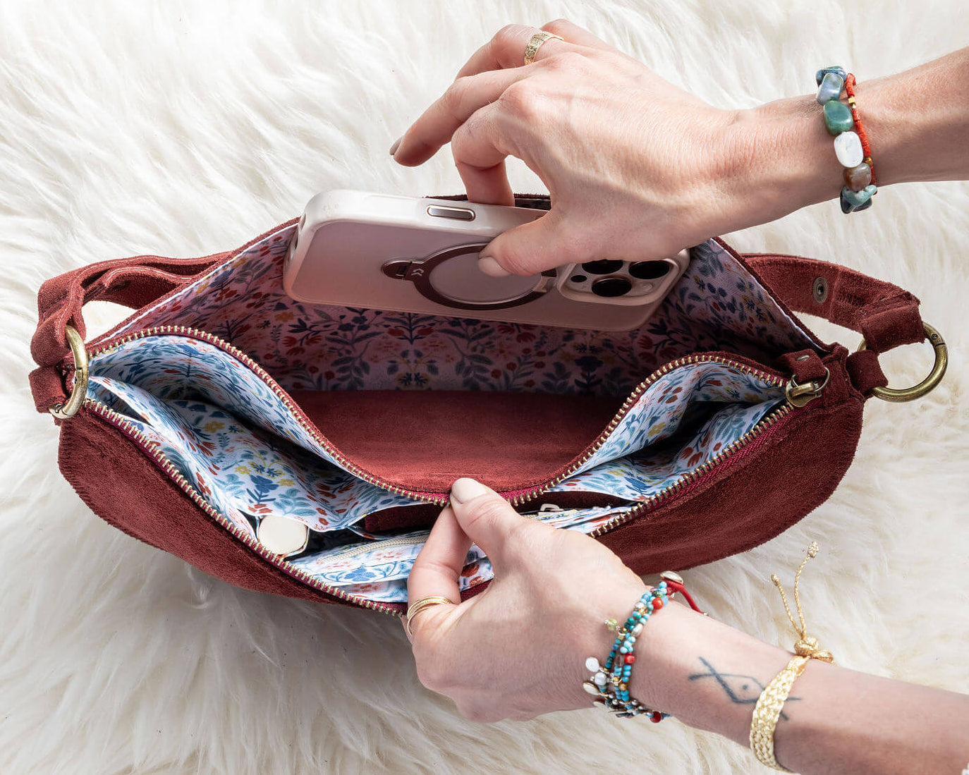 Person opening a red handbag on a white fluffy surface