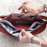 Person opening a red handbag on a white fluffy surface