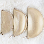 Three beige pouches labeled 'The Bee', 'The Bigger Bee', and 'The Queen Bee' on a white fur background.