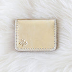 Beige cardholder with a brand logo on a white fur background