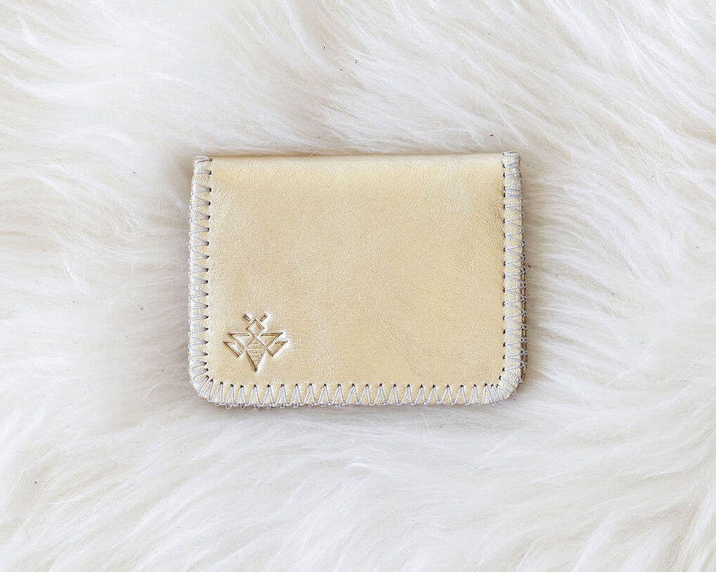 Beige cardholder with a brand logo on a white fur background