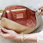 Close-up of a beige handbag with a gold zipper on a white fur background