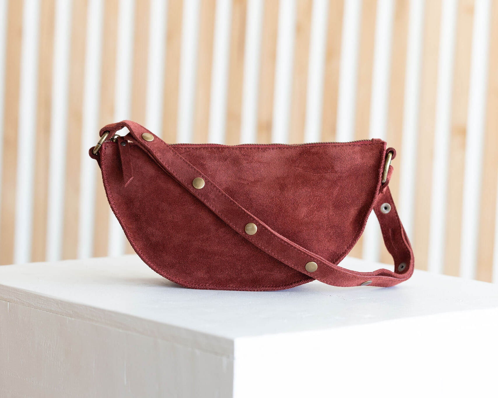 Red handbag on a white surface with a light wooden background