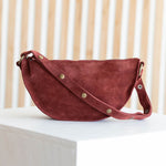 Red handbag on a white surface with a light wooden background