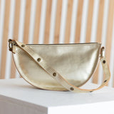 Gold handbag on a white surface with a beige curtain background