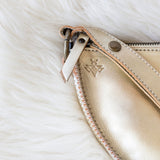 Close-up of a beige leather clutch with a brand logo on a white fur background
