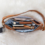 Open brown leather bag with items on a white fluffy surface