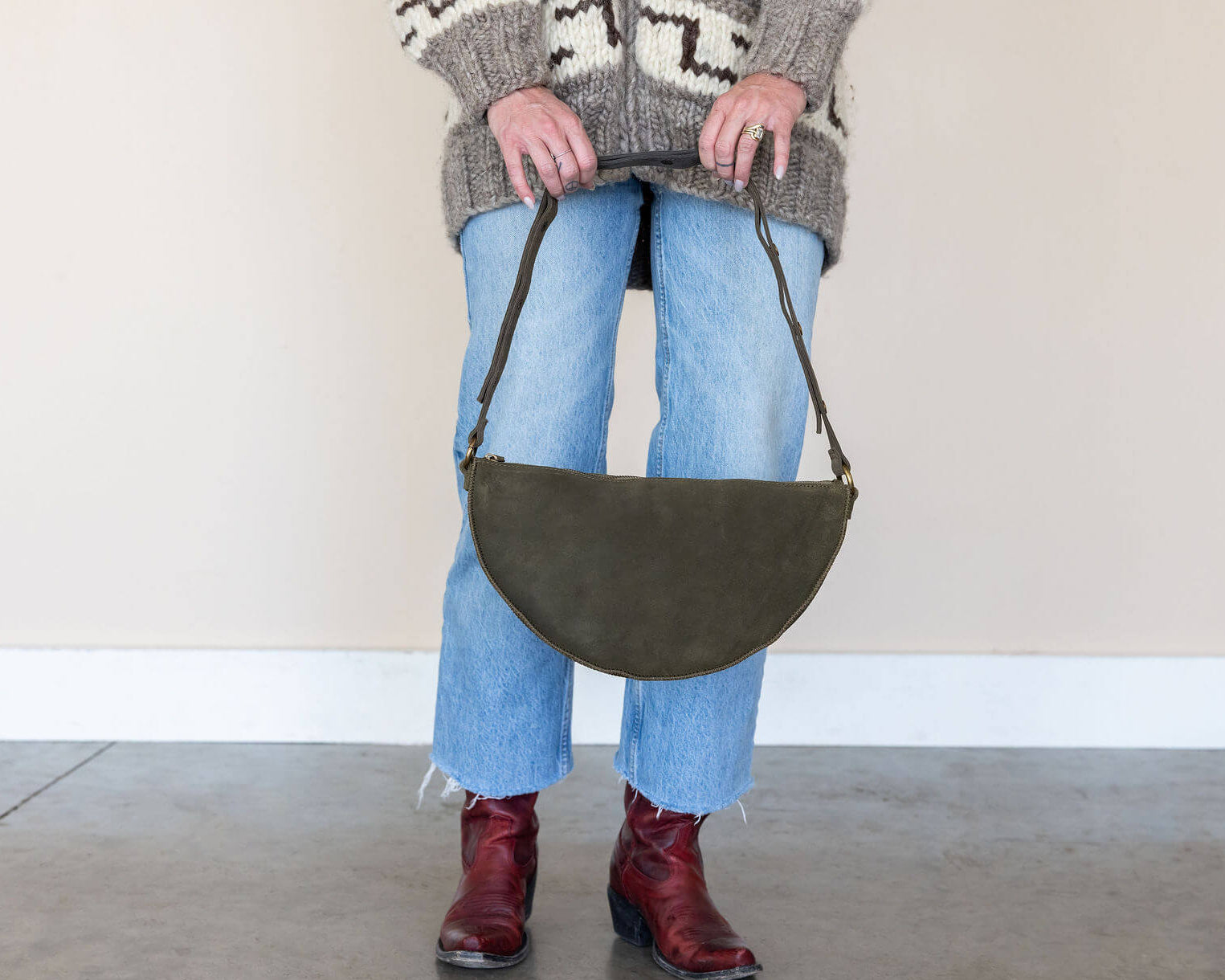 Person holding a green bag with a neutral background
