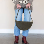 Person holding a green bag with a neutral background