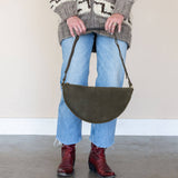 Person holding a green bag with a neutral background