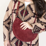 Person wearing a patterned coat holding a red handbag against a white background