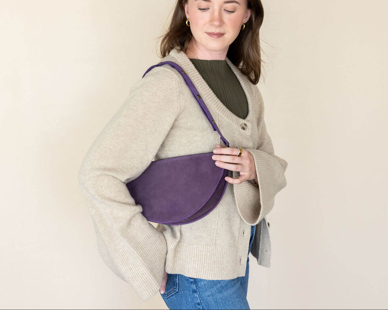Woman holding a purple bag against a plain background