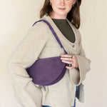 Woman holding a purple bag against a plain background