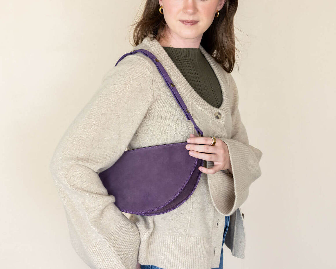 Woman holding a purple bag against a plain background