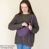 Woman holding a purple bag against a beige background