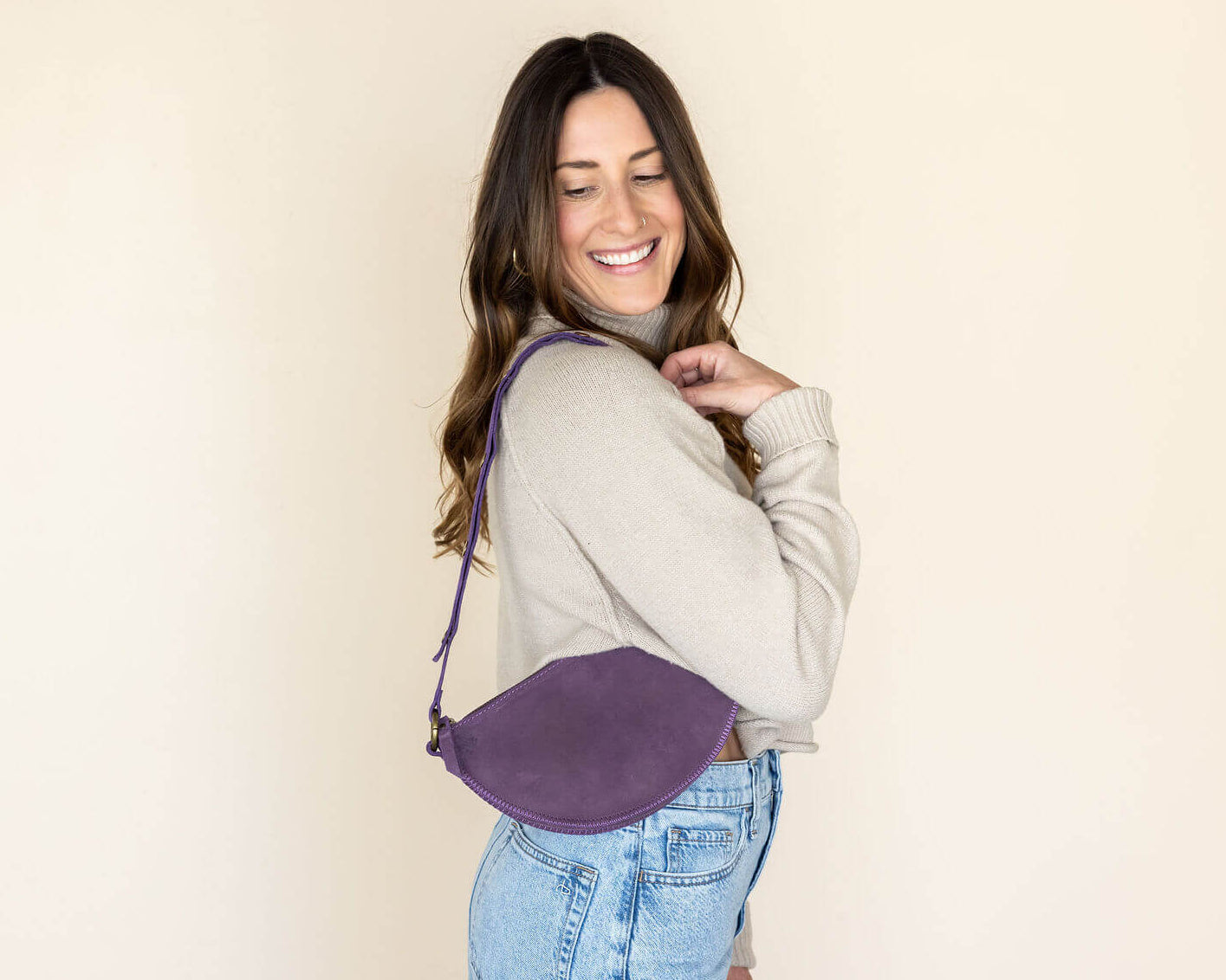 Woman wearing a purple crossbody bag against a beige background