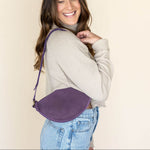Woman wearing a purple crossbody bag against a beige background