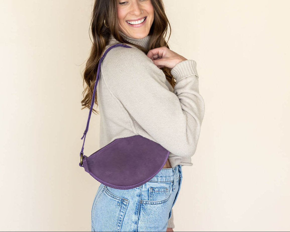 Woman wearing a purple crossbody bag against a beige background