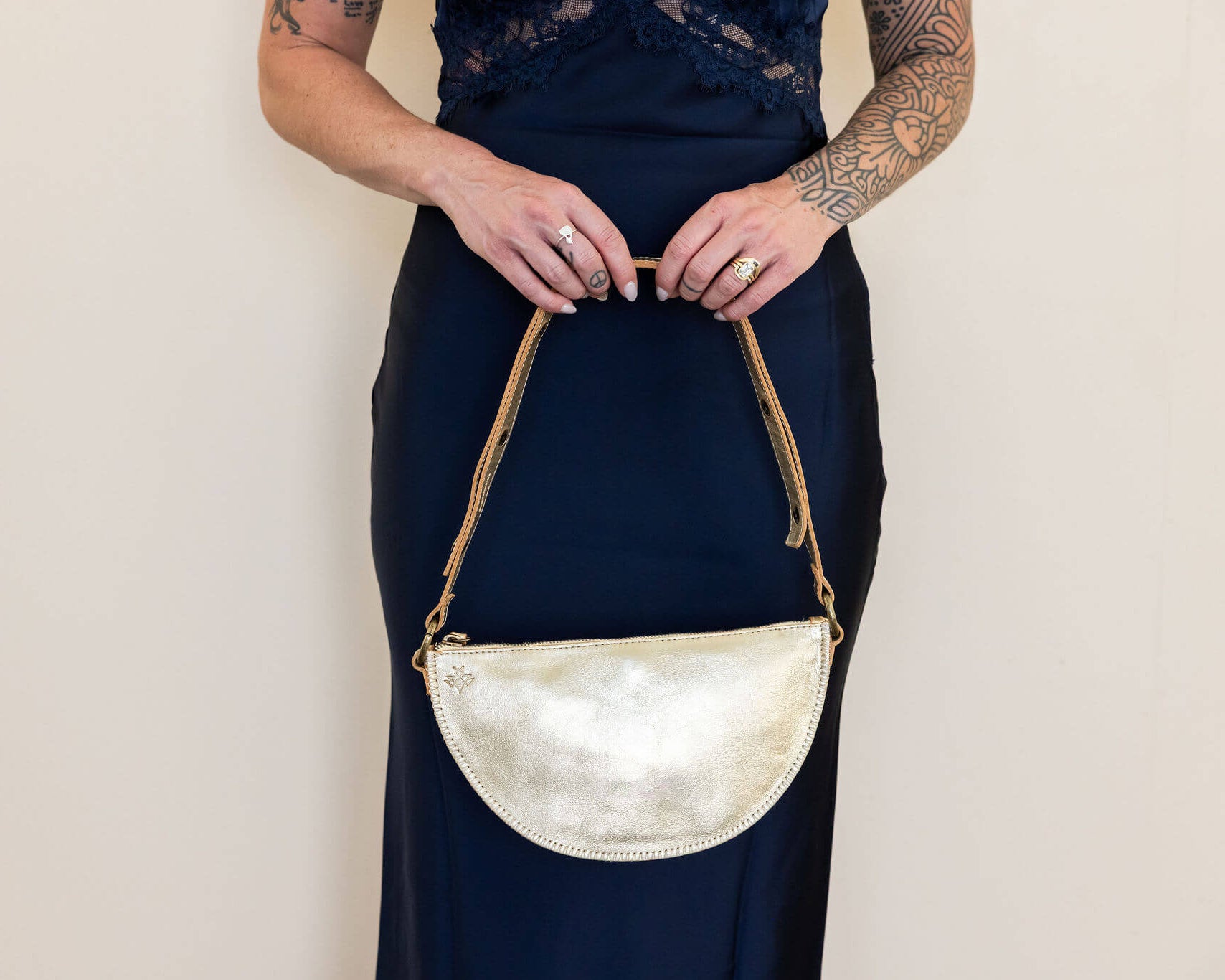 Person holding a gold handbag against a plain background
